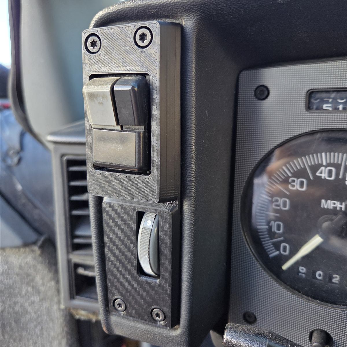 Reproduction Fiero driver-side cluster panel installed beside the speedometer, with the factory headlight switch and dimmer wheel