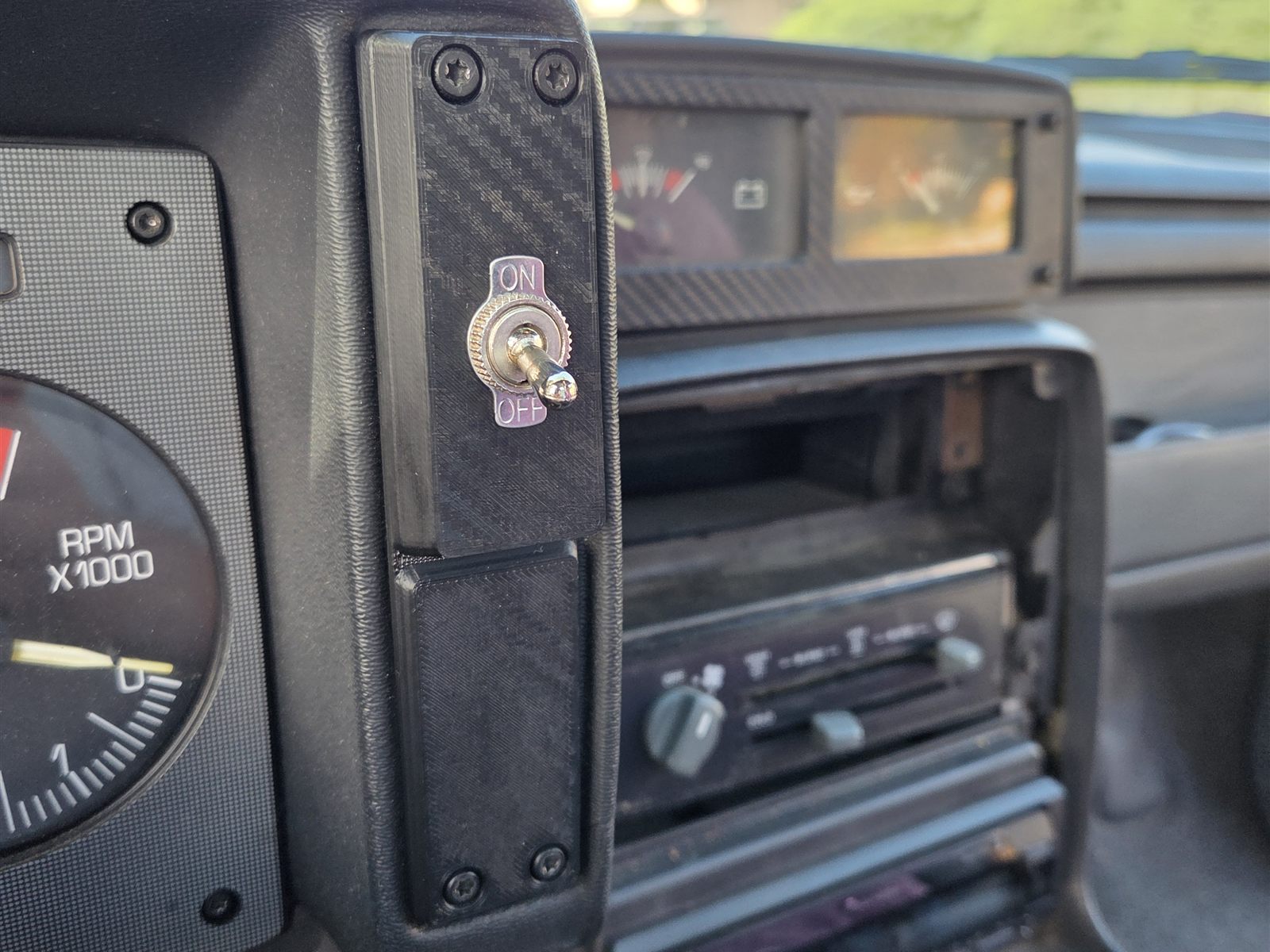Reproduction Fiero passenger-side cluster trim installed beside the tachometer, with a toggle switch