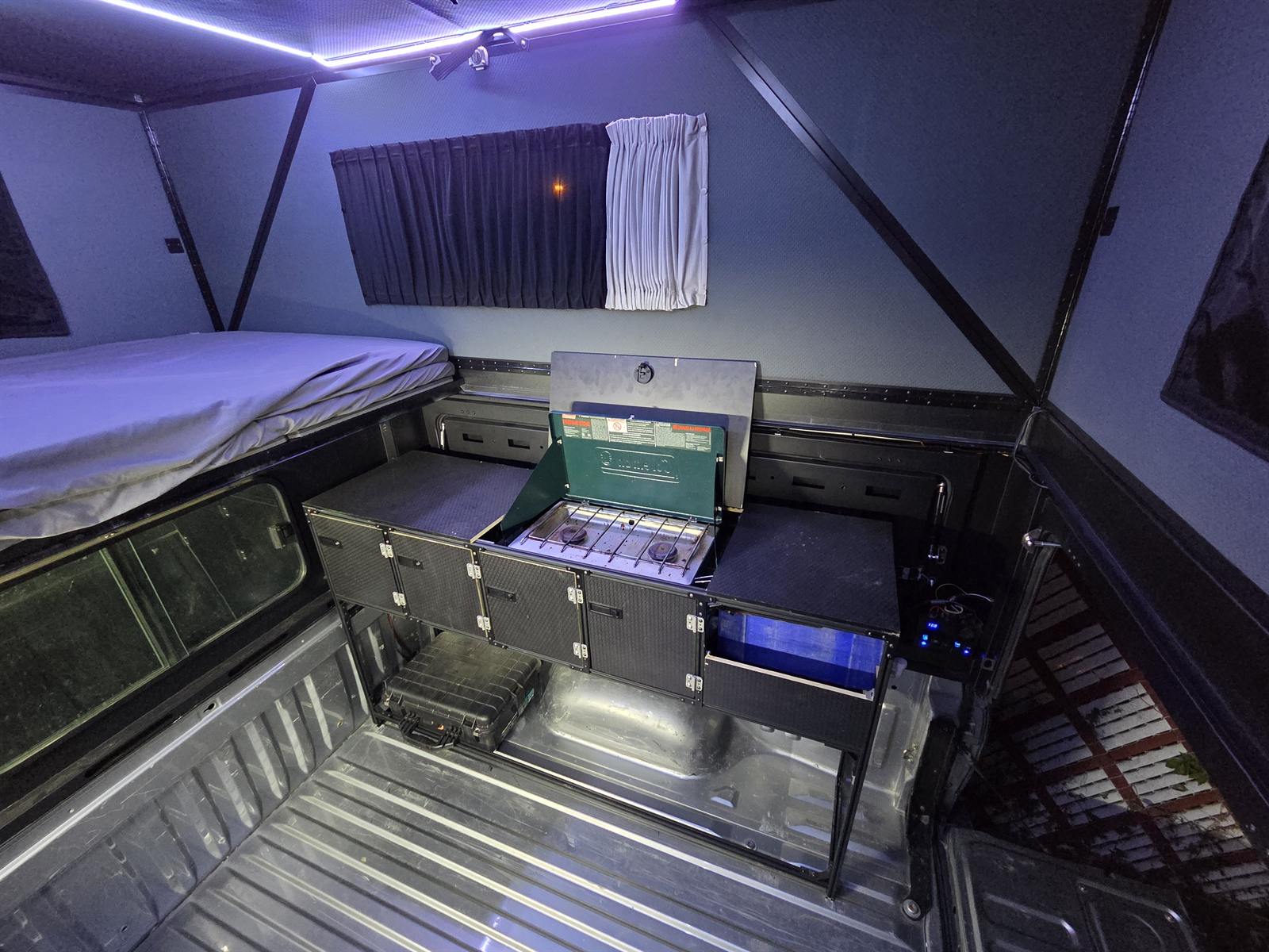 The same galley cabinet set up for camp, with the stove tray open and a two-burner camp stove ready to cook