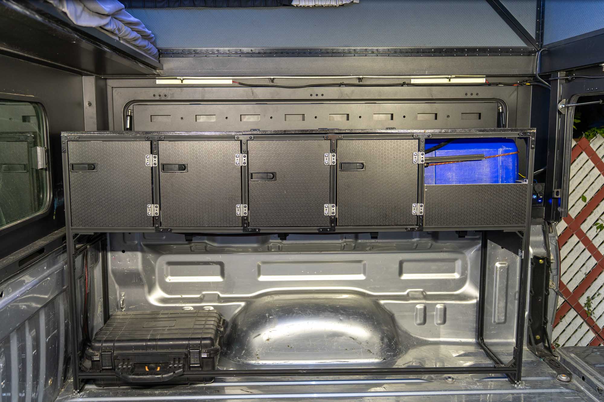 Removable galley cabinet installed across the front of a truck bed, doors closed, with open floor below