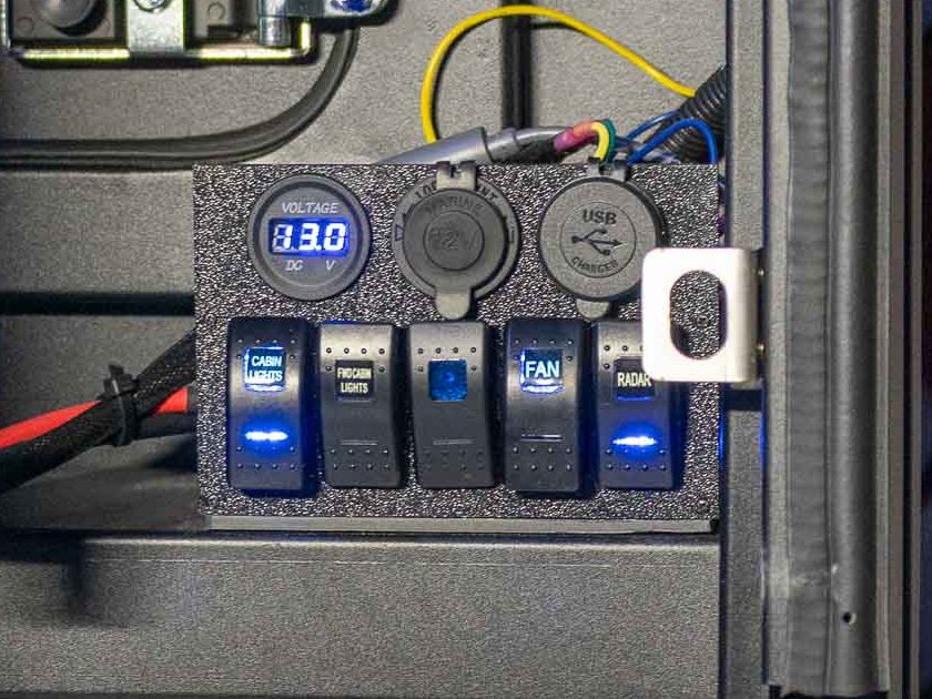 Camper switch panel with a voltmeter, 12V and USB outlets, and lighted switches for cabin lights, fan and radar
