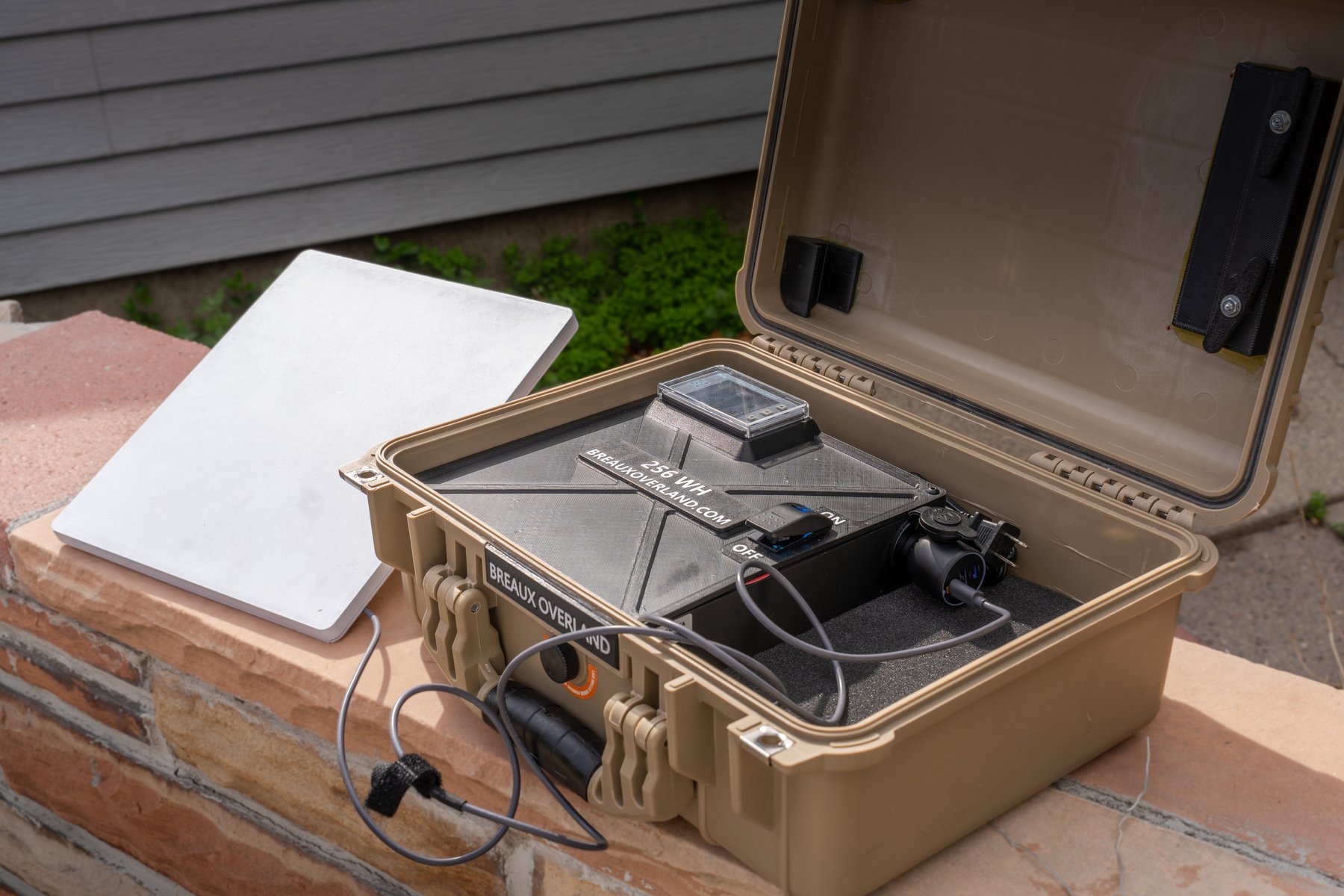 Open Starlink Mini power kit at an angle, dish leaning beside the case, battery box switched on
