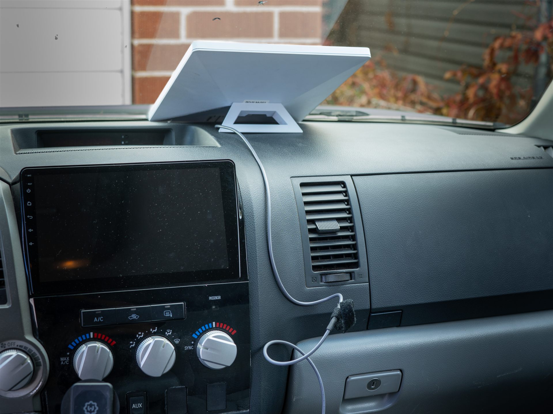 Starlink Mini dish set up on a truck dashboard, its cable running to a USB charger in the console